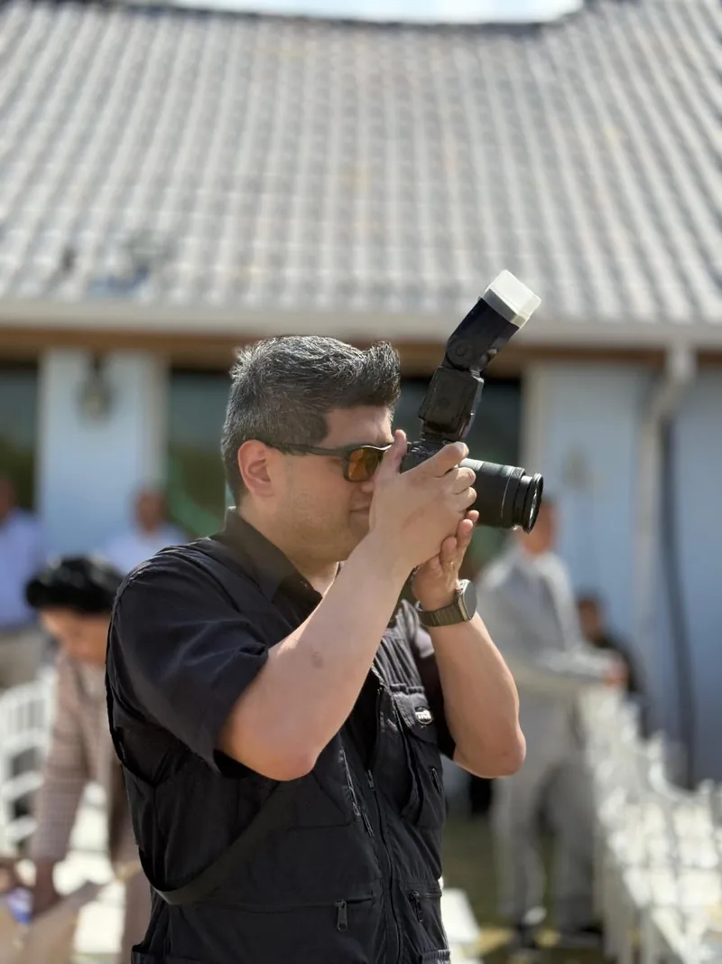 Fernando fotografando durante o evento, com a câmera no rosto e o flash montado