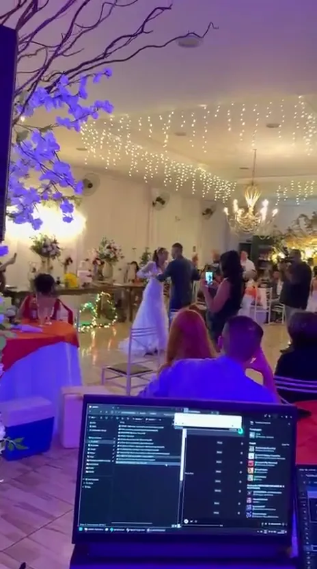 Noivos na pista, vistos do posto do DJ, sob as luzes do salão