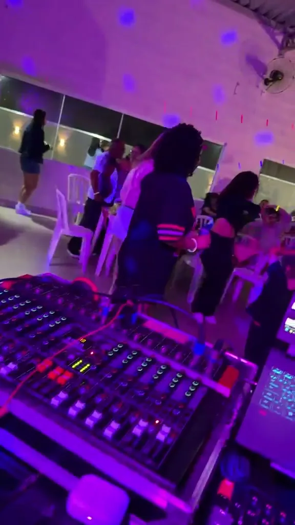 Mesa de som de 12 canais em primeiro plano, com a festa acontecendo atrás