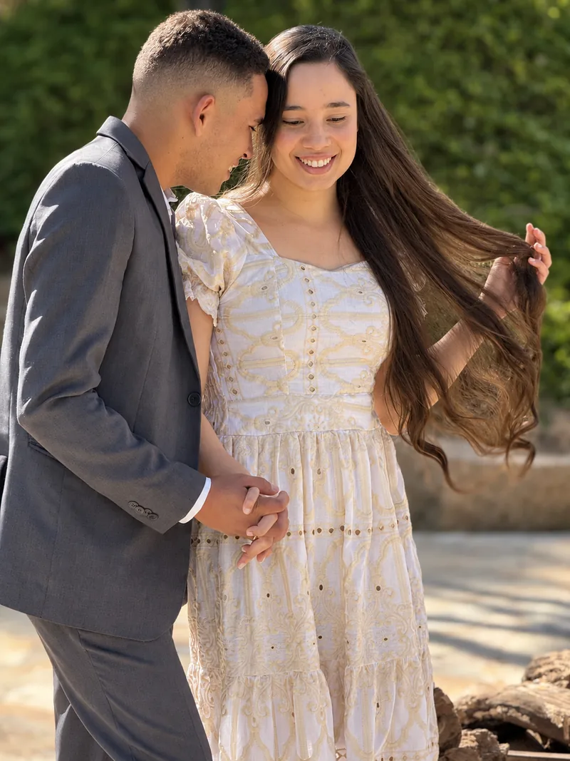 Casal em ensaio ao ar livre, ele acariciando o cabelo dela