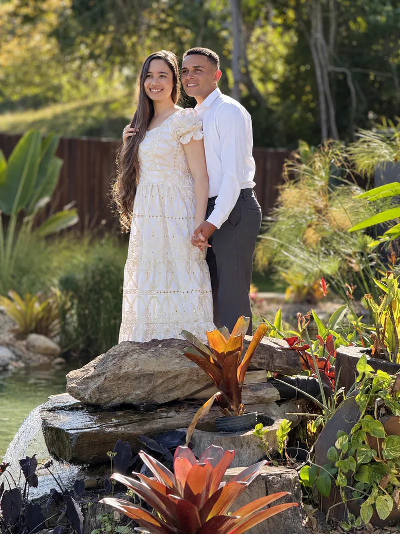 Casal de pé em um jardim, durante o ensaio
