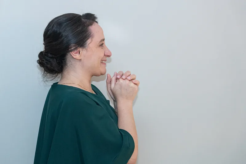 Mãe de mãos juntas, emocionada, assistindo à festa