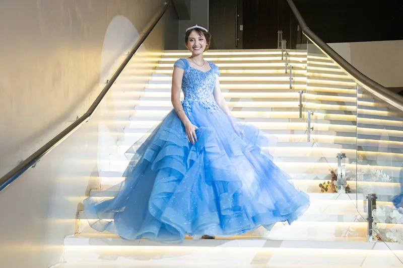 Debutante descendo a escada iluminada, com vestido azul