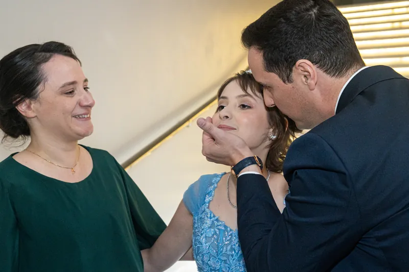 Os pais beijando a debutante, um de cada lado