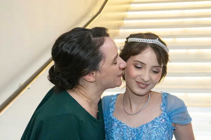 Mãe beijando o rosto da debutante
