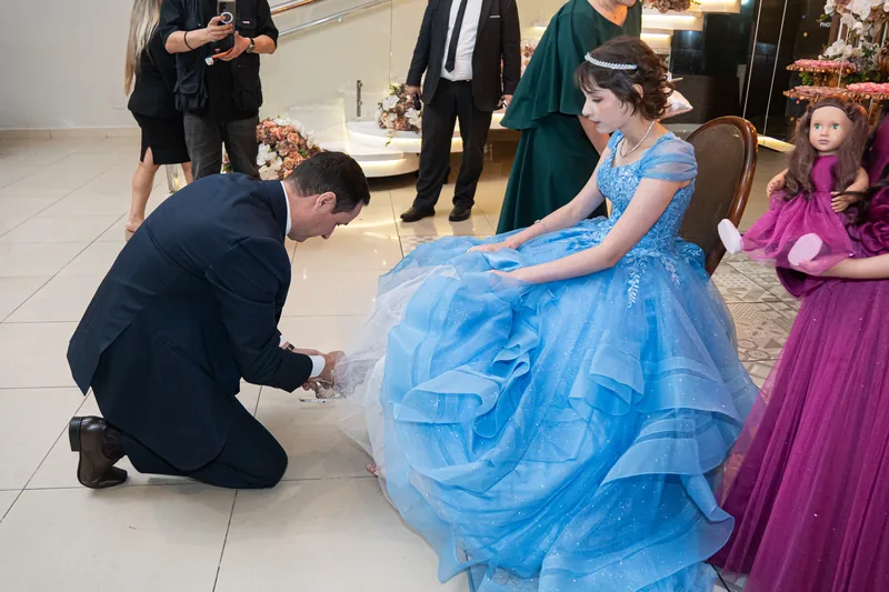 Pai ajoelhado trocando o sapato da debutante