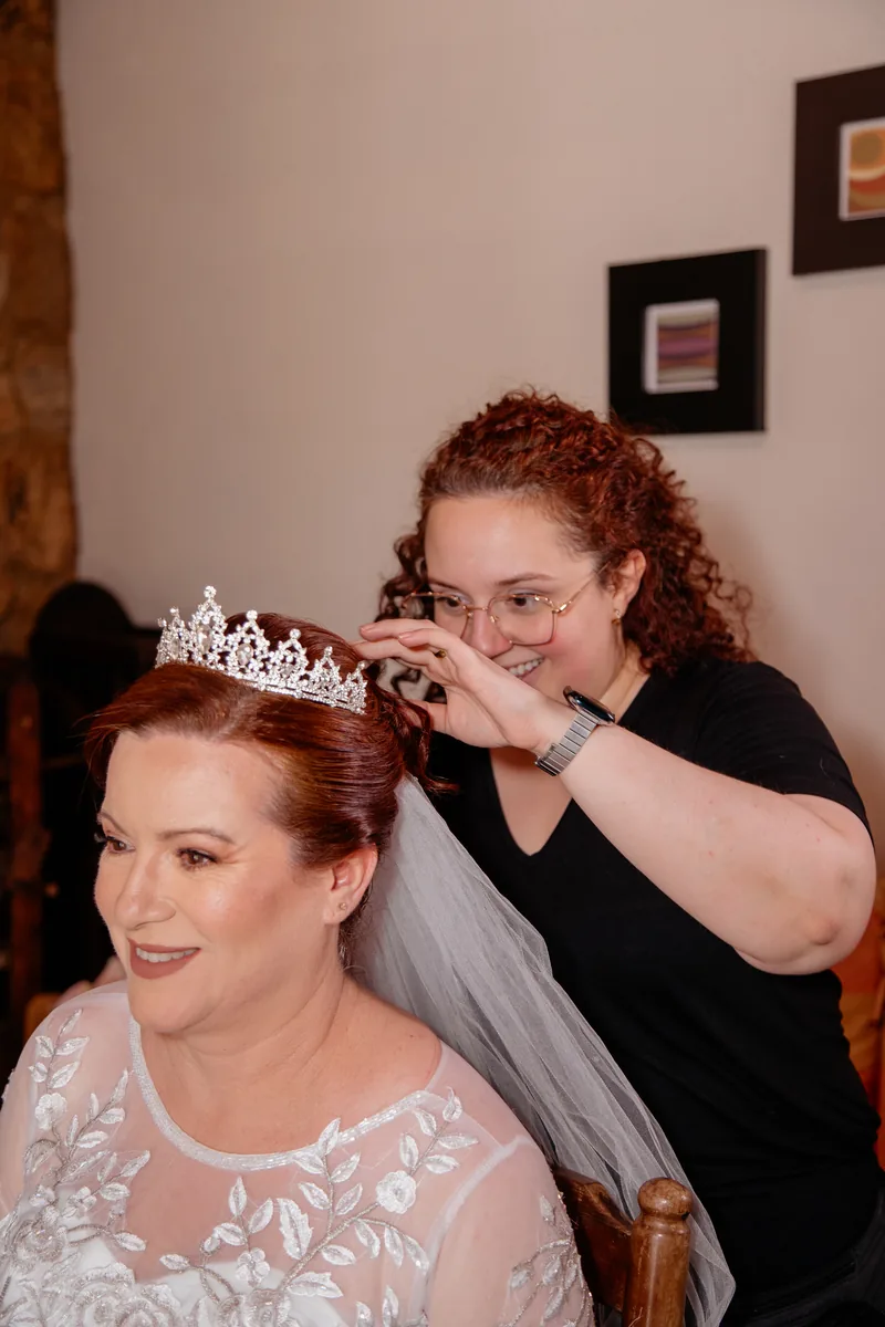 Nathalia posicionando a coroa no penteado da noiva