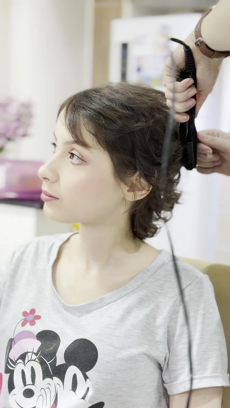 Cliente de perfil enquanto o cabelo é cacheado, fio a fio